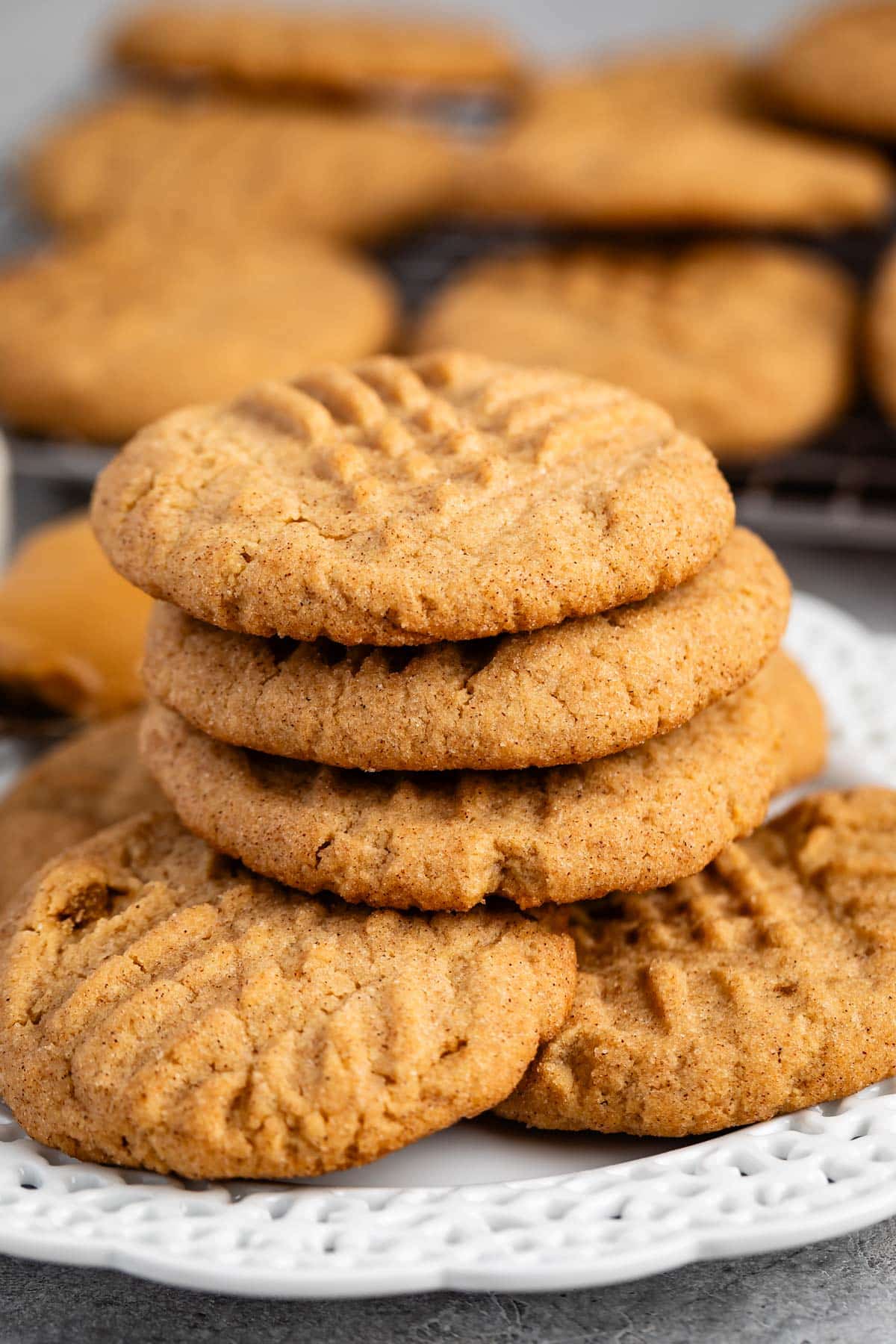 stacked peanut butter snickerdoodles on a white plate next to a spoonful of peanut butter.