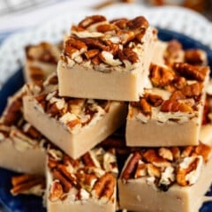 stacked pecan fudge with chopped pecan pressed on top on a blue plate.