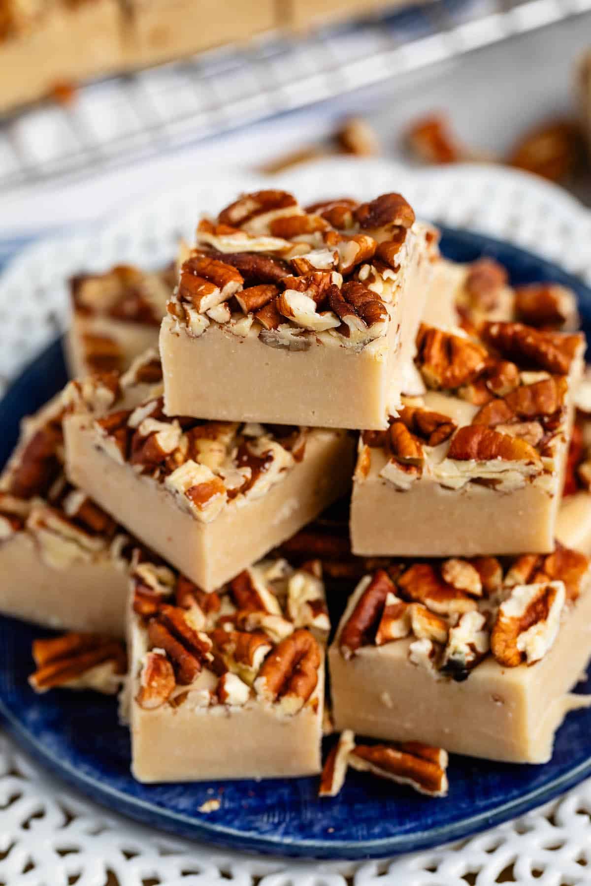 stacked pecan fudge with chopped pecan pressed on top on a blue plate.