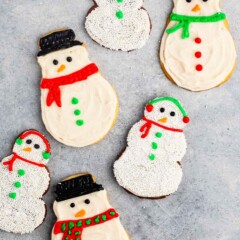 snowman cookies covered in white frosting and sprinkles and icing to replicate a snowman.