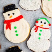 snowman cookies covered in white frosting and sprinkles and icing to replicate a snowman.