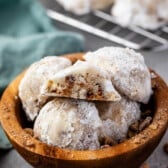 stacked snowballs covered in powdered sugar in a wood bowl.