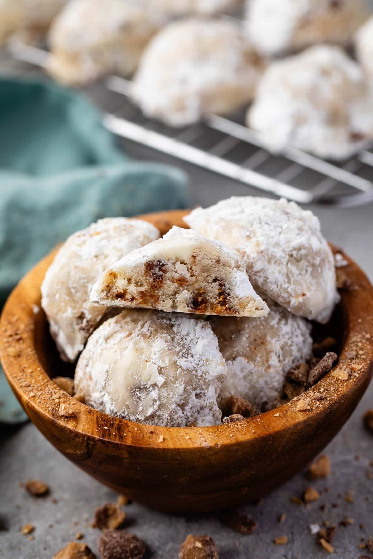 stacked snowballs covered in powdered sugar in a wood bowl.