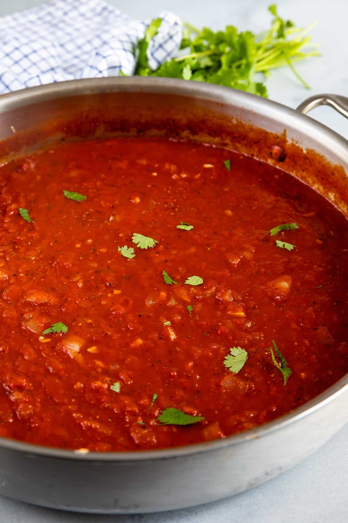 pasta sauce in a sliver pan with greens on top.