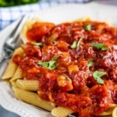 red pasta sauce on top of pasta on a white plate.
