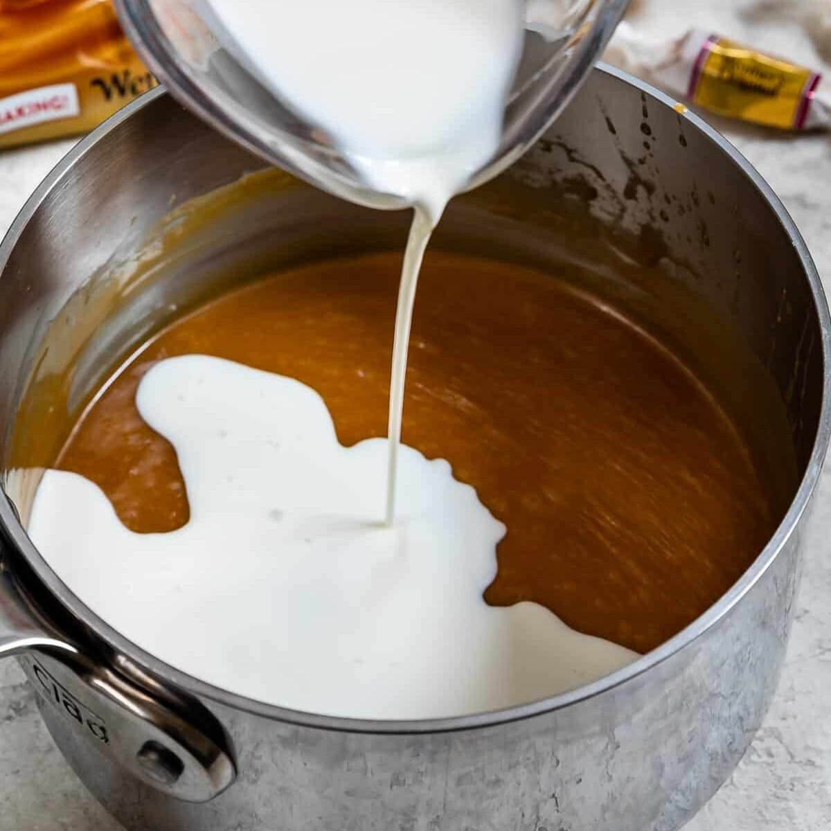 cream pouring into pan of caramel sauce.