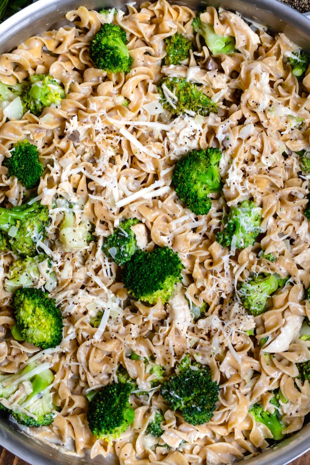 pasta mixed with broccoli in a silver skillet.