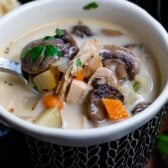 soup with mushrooms in it in a dark blue bowl with a spoon inside.
