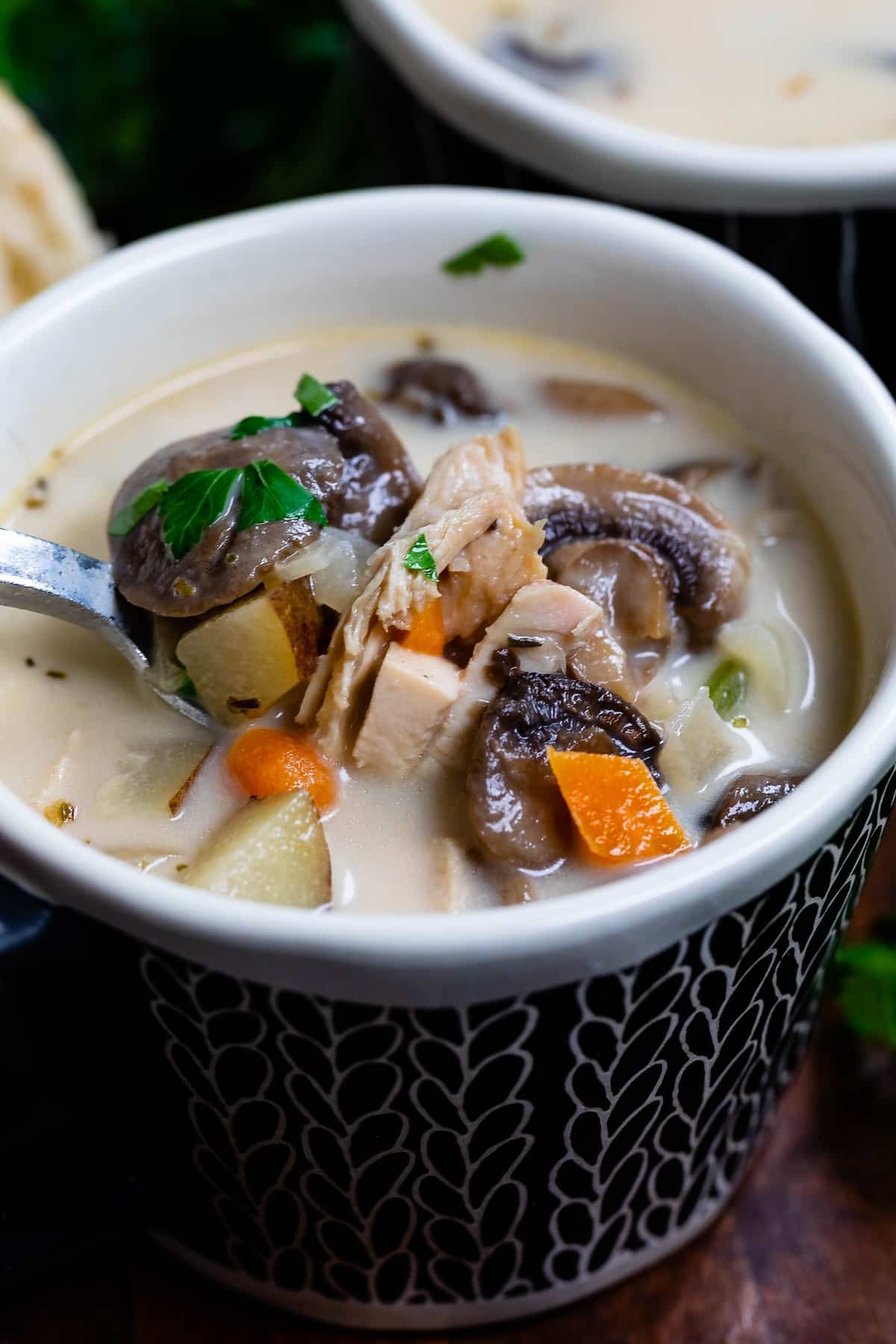 soup with mushrooms in it in a dark blue bowl with a spoon inside.