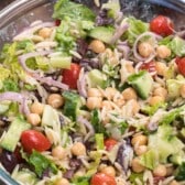 salad mixed together with dressing in a clear bowl.