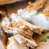 chicken on a cutting board with greens sprinkled on top.