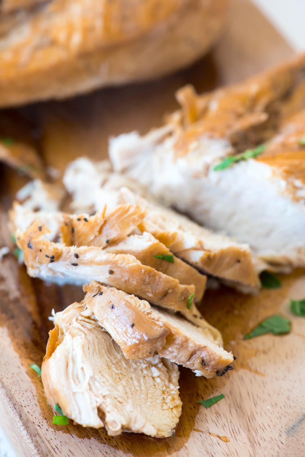 chicken on a cutting board with greens sprinkled on top.