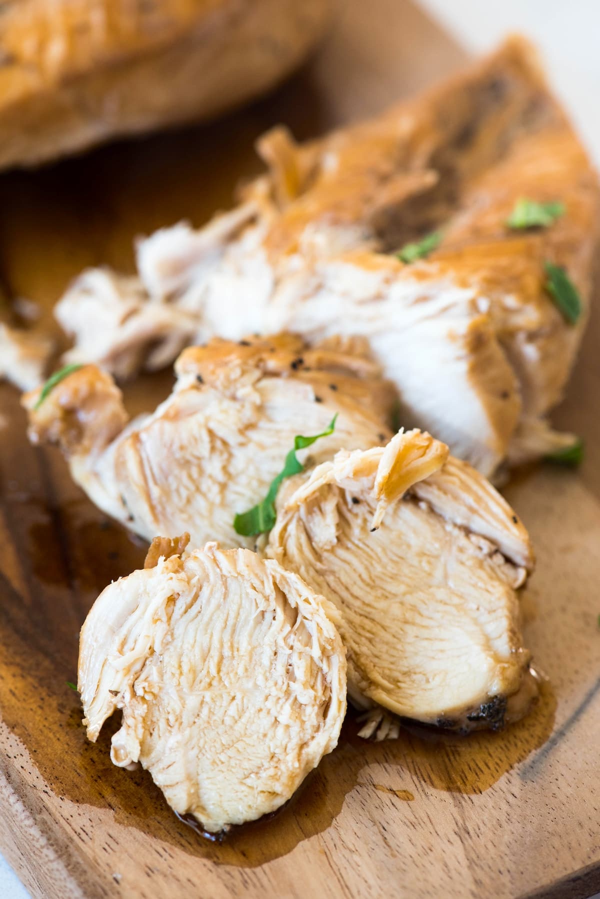 chicken on a cutting board with greens sprinkled on top.