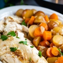 chicken and carrots and potatoes in a white bowl with an instant pot in the back.