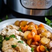 chicken and carrots and potatoes in a white bowl with an instant pot in the back.