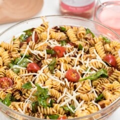 salad mixed with tomatoes and cheese in a clear bowl.