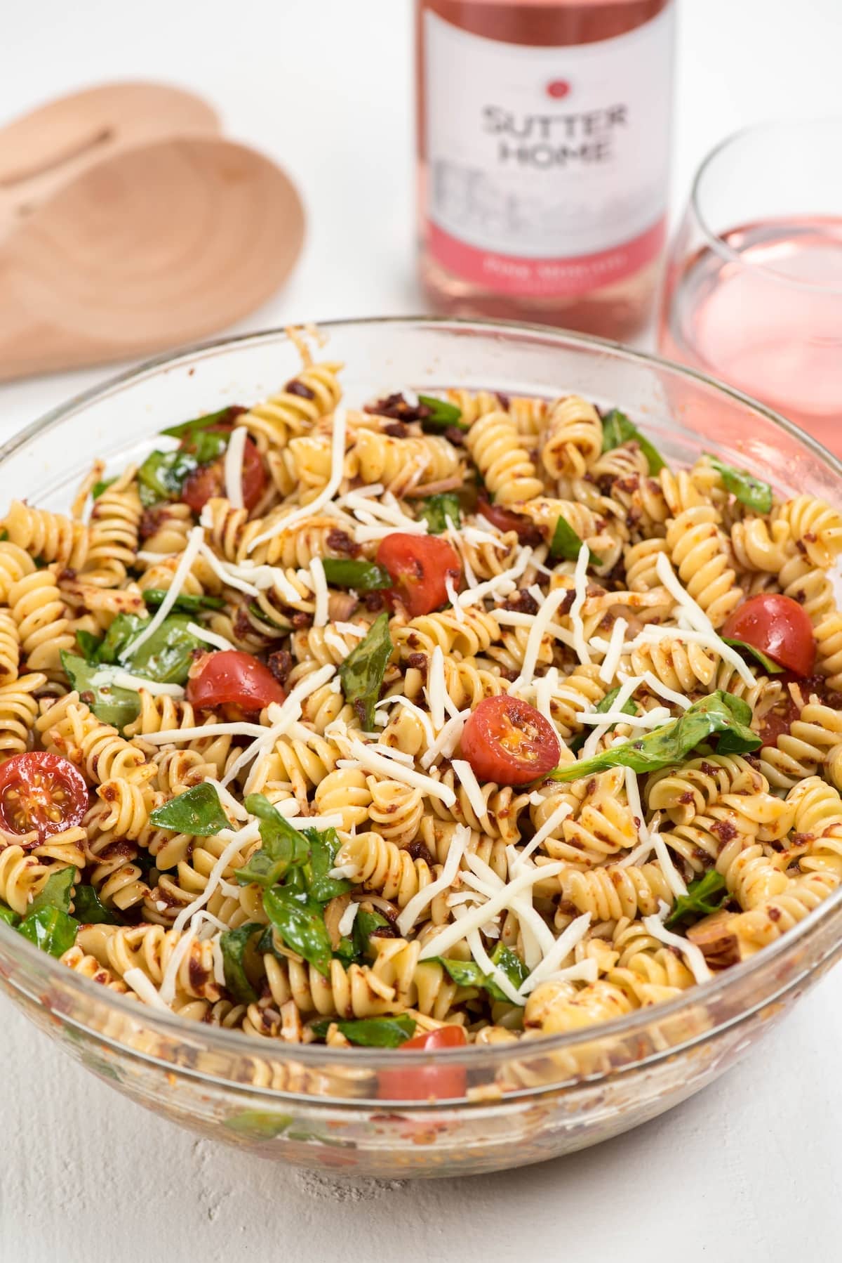 salad mixed with tomatoes and cheese in a clear bowl.