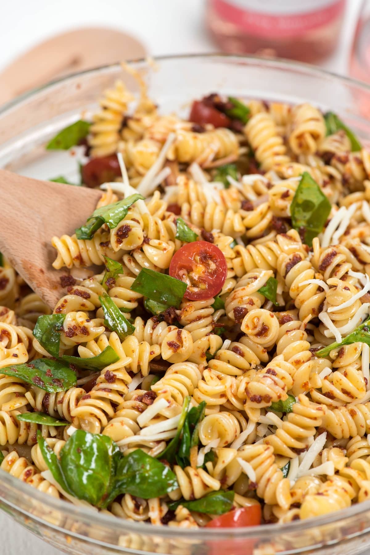 salad mixed with tomatoes and cheese in a clear bowl.