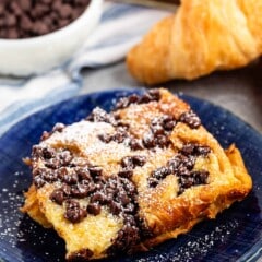 French toast on a blue plate with chocolate chips and powdered sugar sprinkled on top.