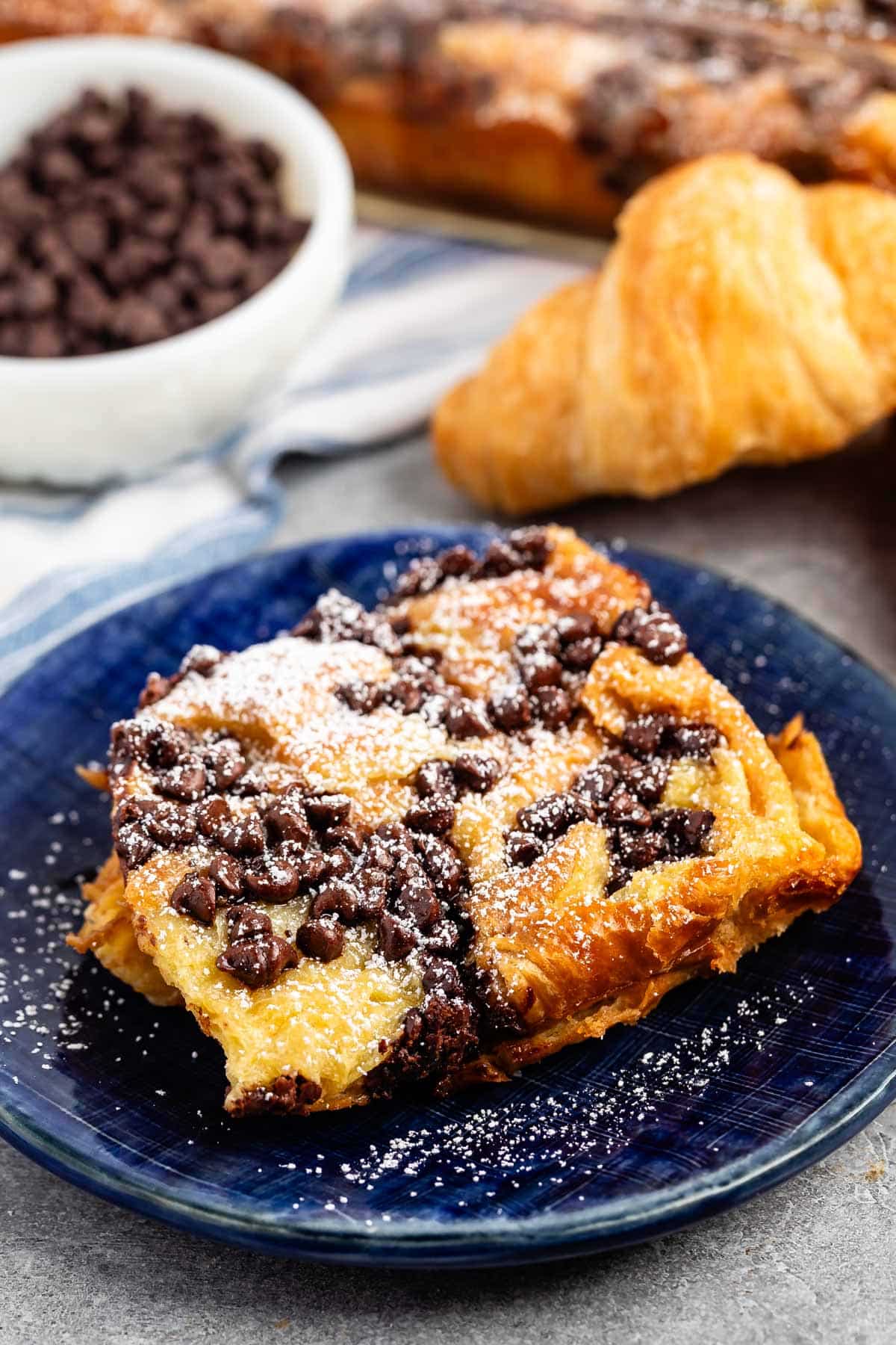 French toast on a blue plate with chocolate chips and powdered sugar sprinkled on top.