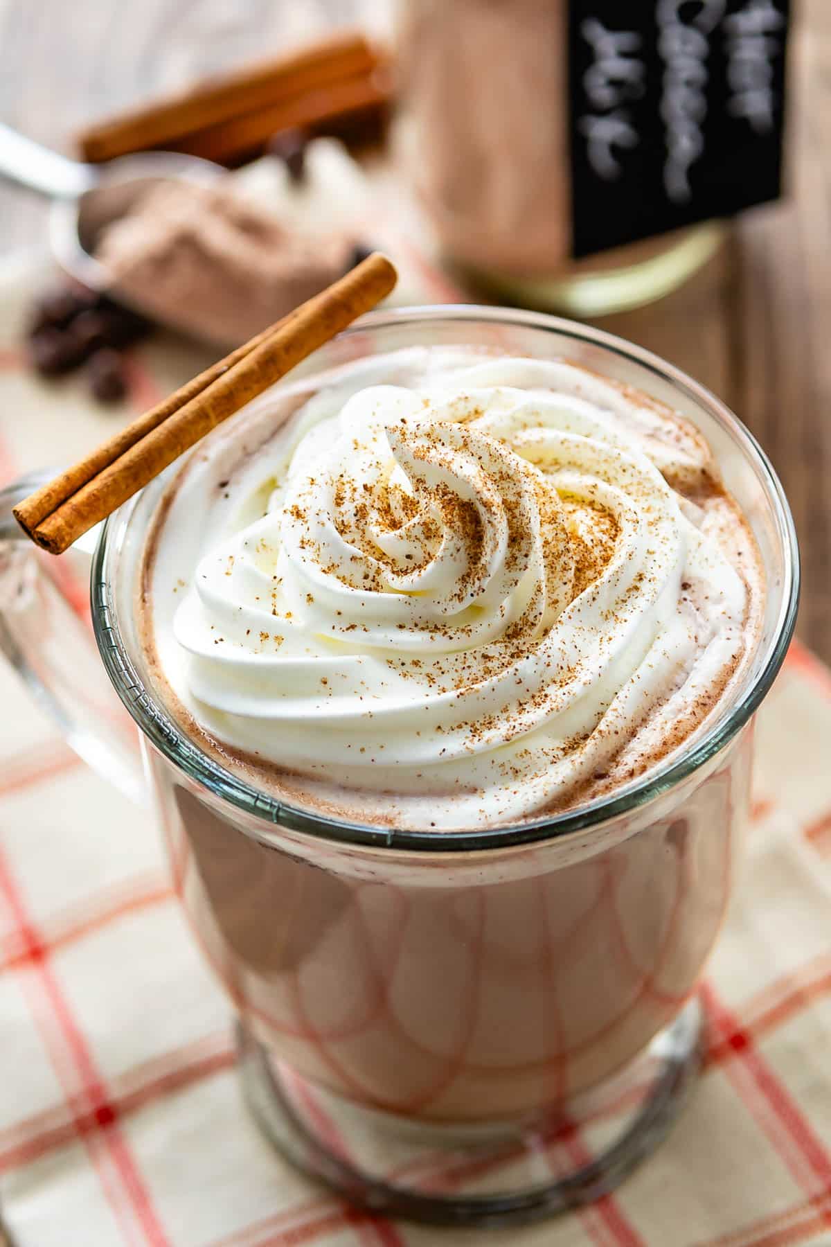 hot chocolate in a clear glass with whipped cream on top.