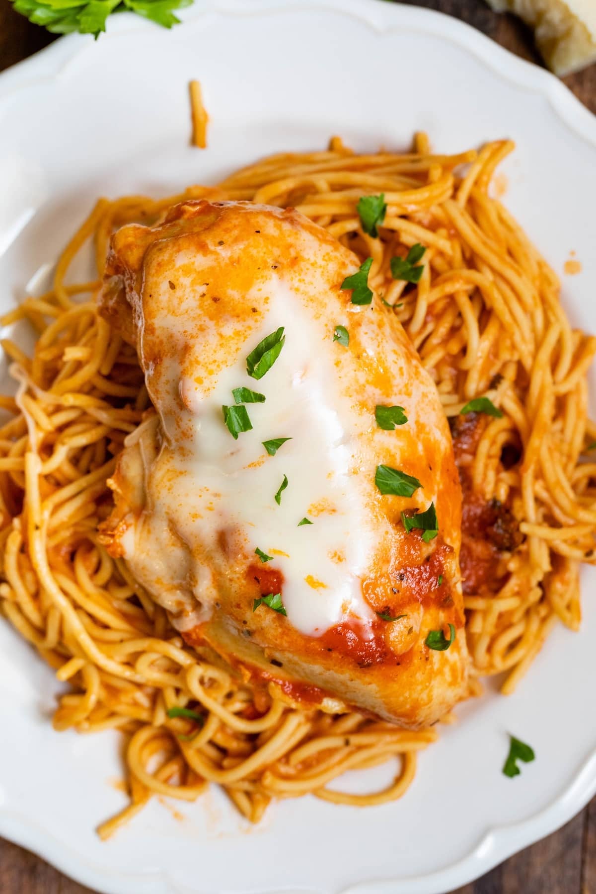 chicken breast on top of spaghetti on a white plate.