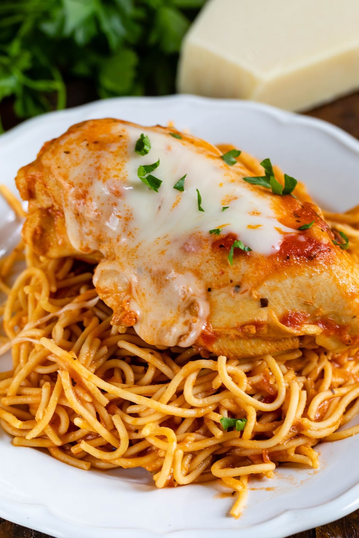 chicken breast on top of spaghetti on a white plate.