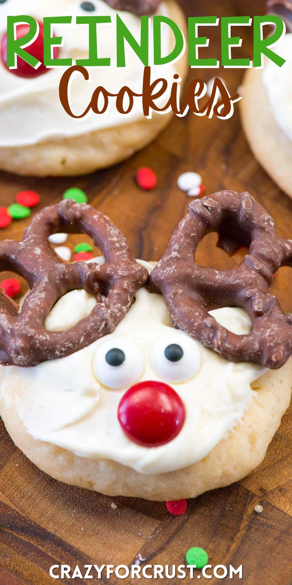 cookie with white frosting and candy on top to make the cookie look like a reindeers face with words on the image.
