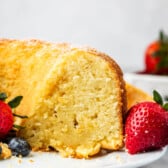 sliced pound cake on a white plate next to strawberries and blueberries.