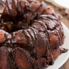 round monkey bread on a white plate with chocolate oozing with the sides.
