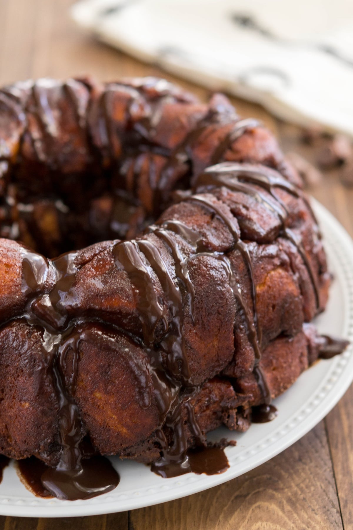 round monkey bread on a white plate with chocolate oozing with the sides.