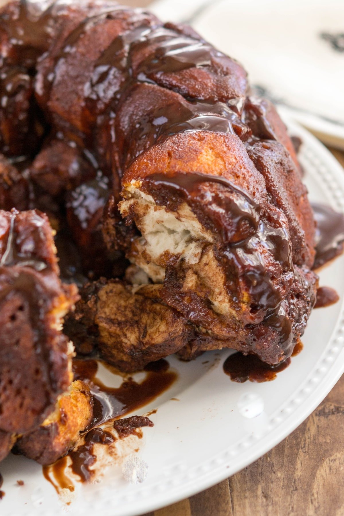round monkey bread on a white plate with chocolate oozing with the sides.