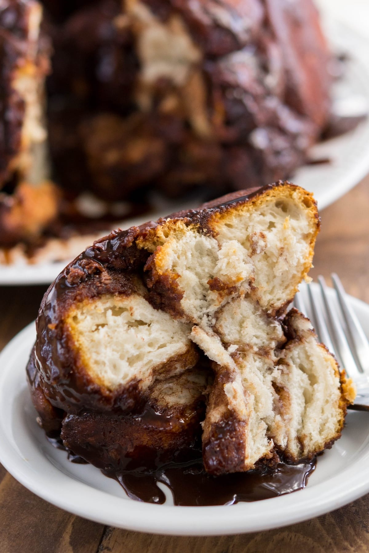 monkey bread sliced on a white plate with chocolate oozing with the sides.