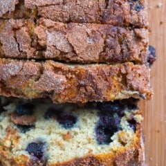 sliced banana bread with blueberries baked in on a cutting board.