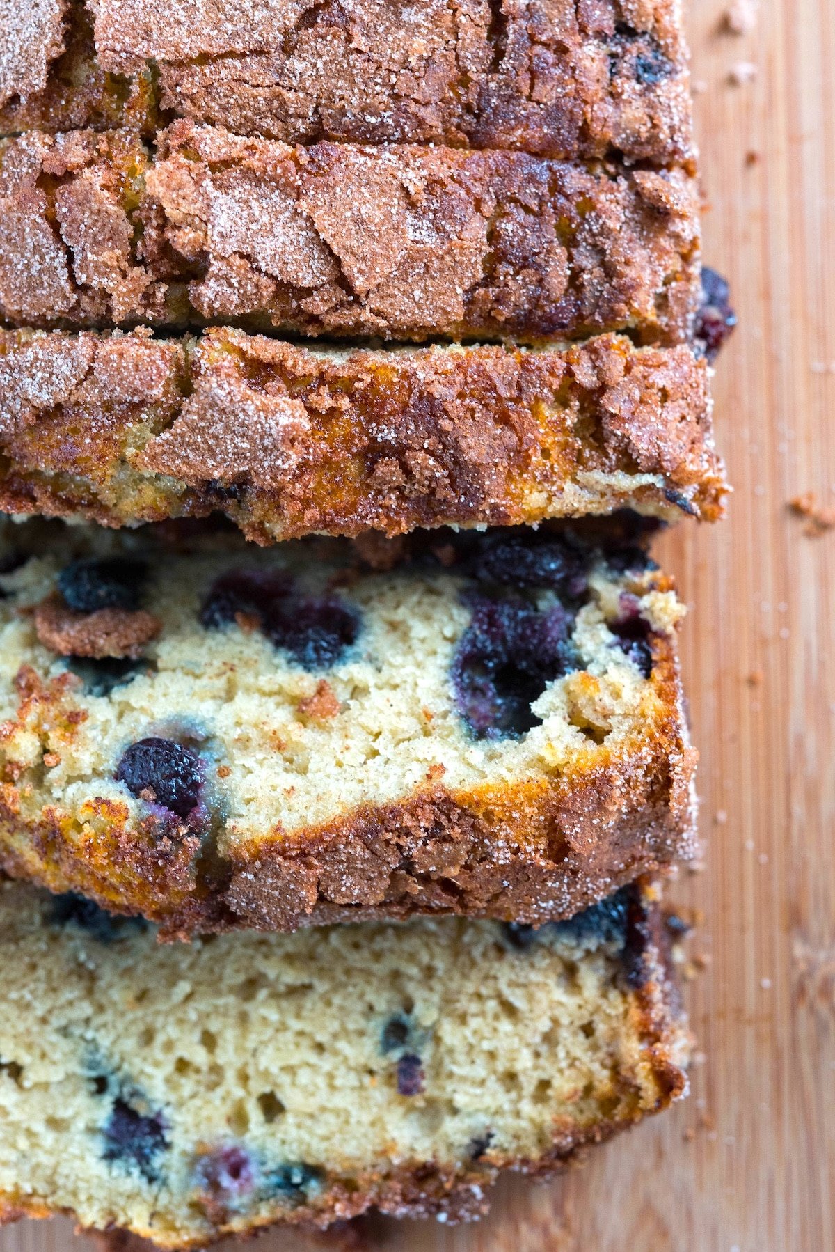 sliced banana bread with blueberries baked in on a cutting board.