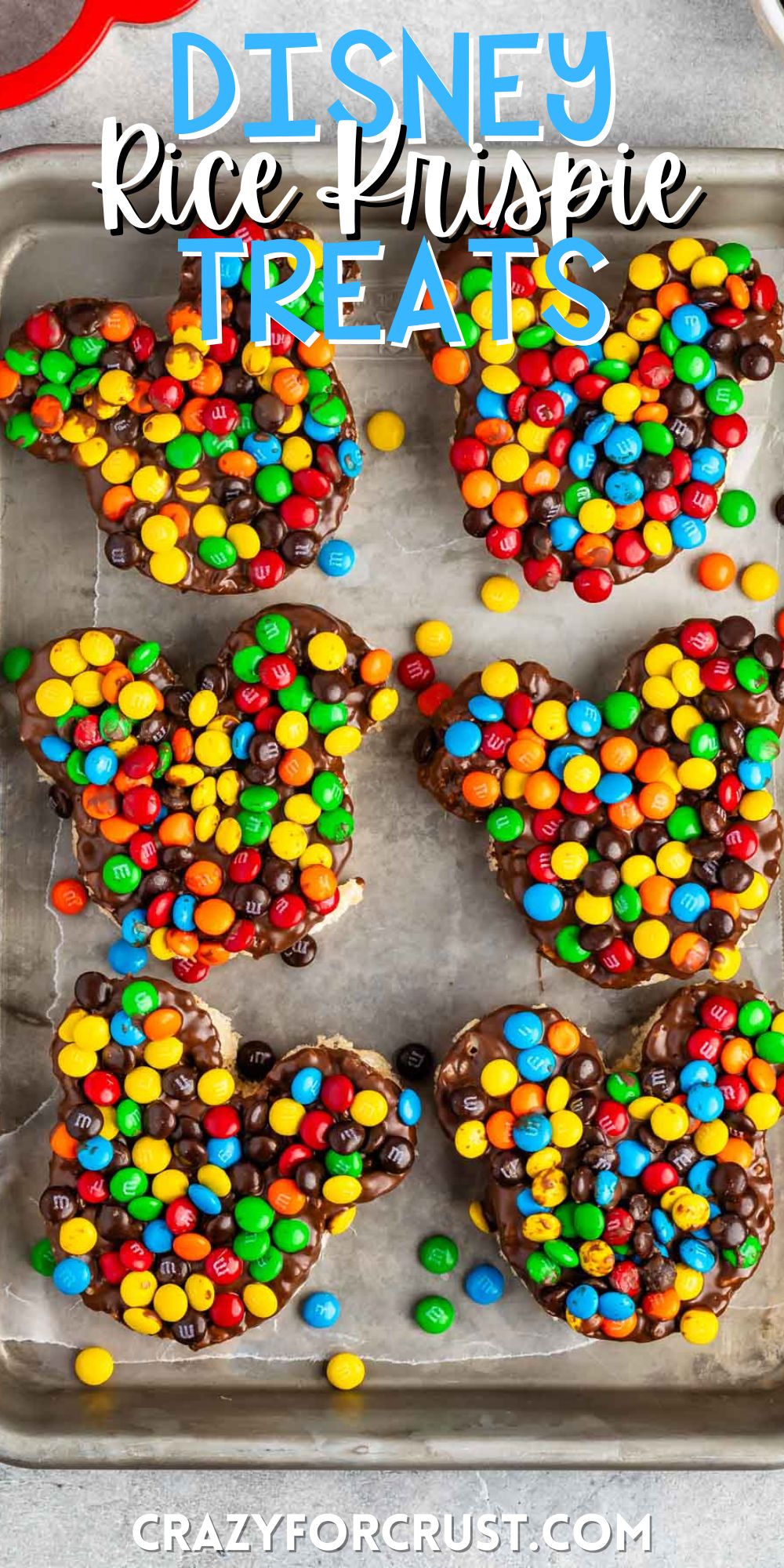 Mickey Mouse shaped Rice Krispie treats covered in chocolate and colorful M&Ms with words on the image.