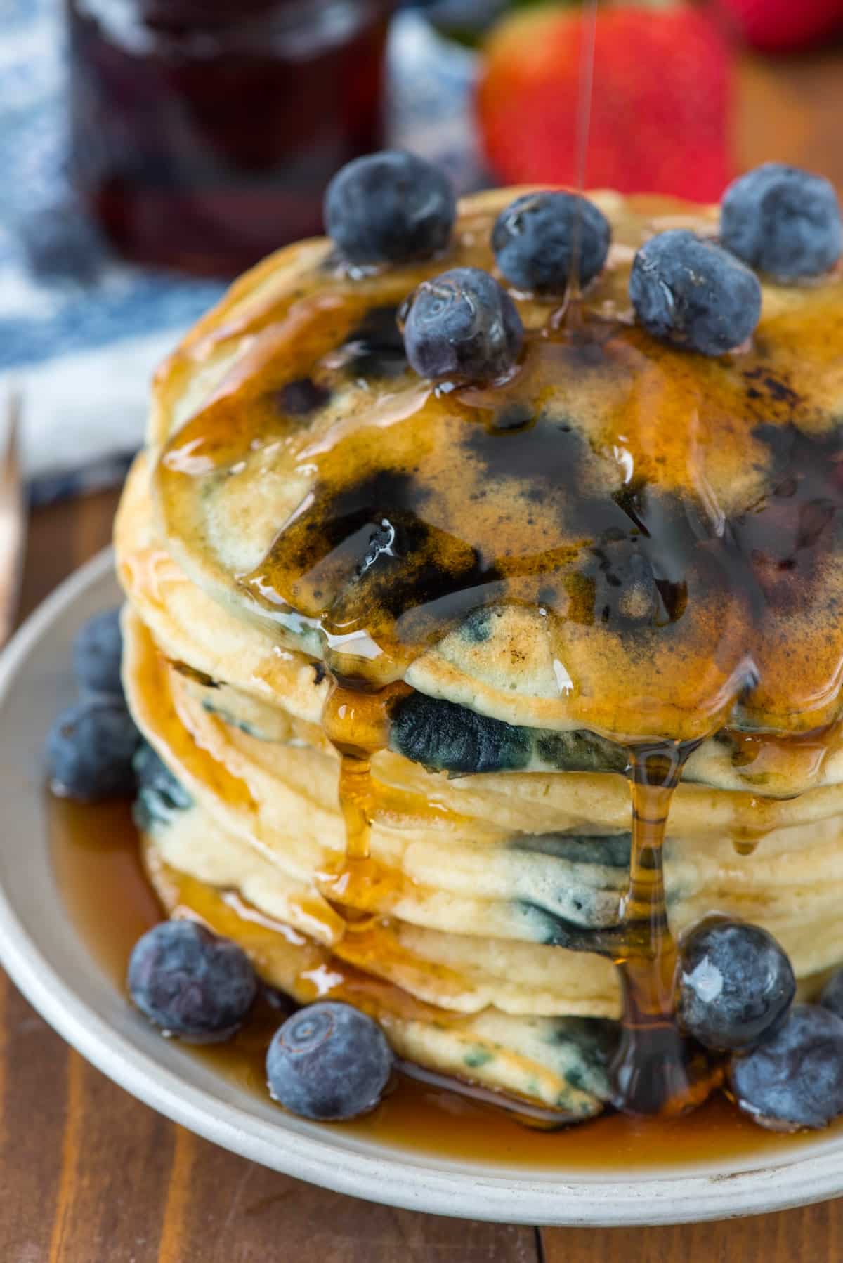 stacked pancakes with blueberries baked in and covered in syrup.