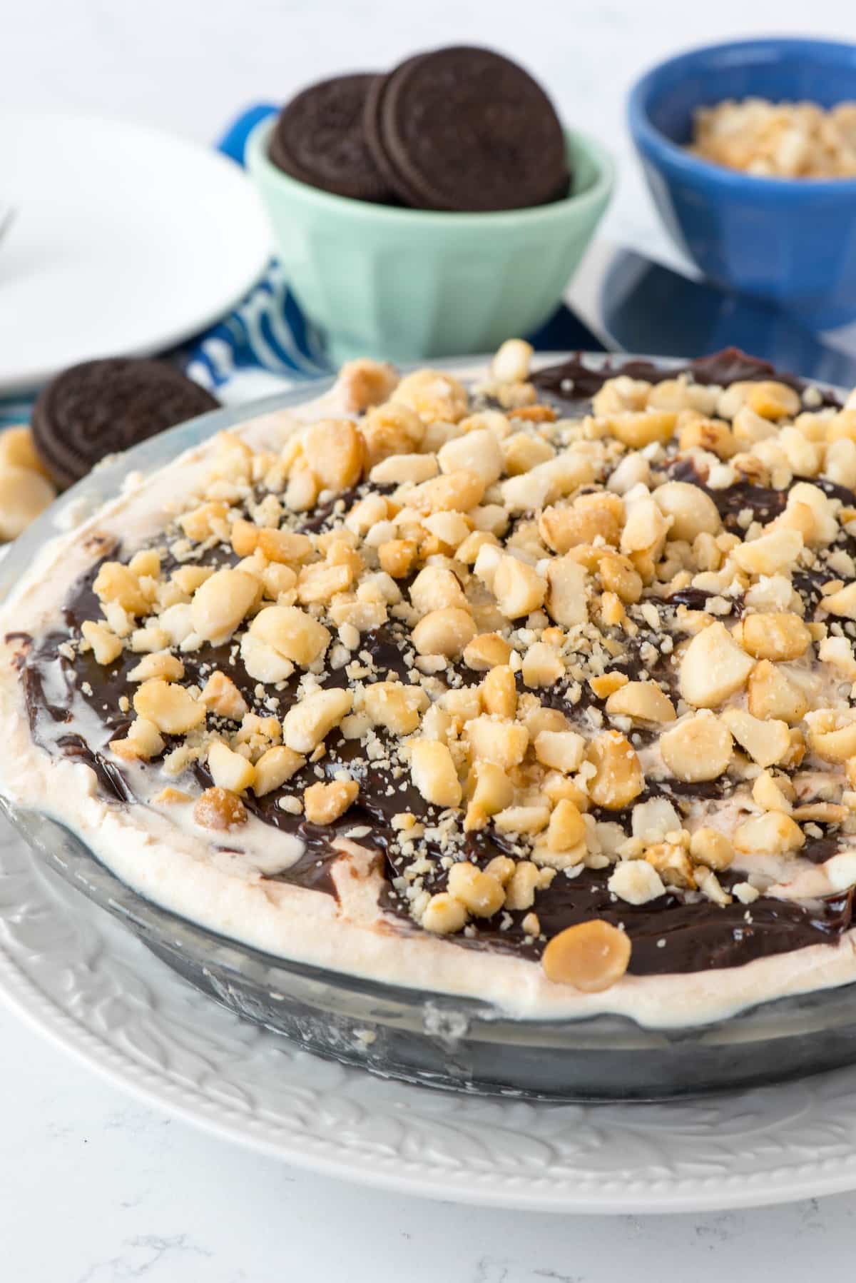 ice cream pie with chocolate sauce and macadamia nuts on top.