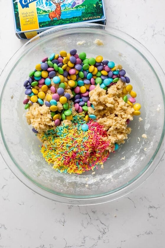 dough in bowl with m&ms and sprinkles with butter box.