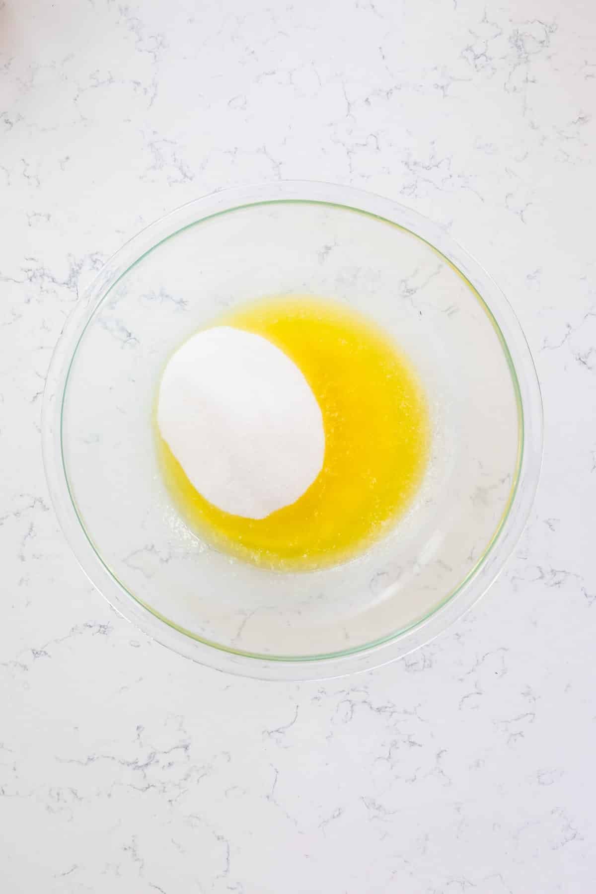 melted butter and sugar in bowl on marble background.