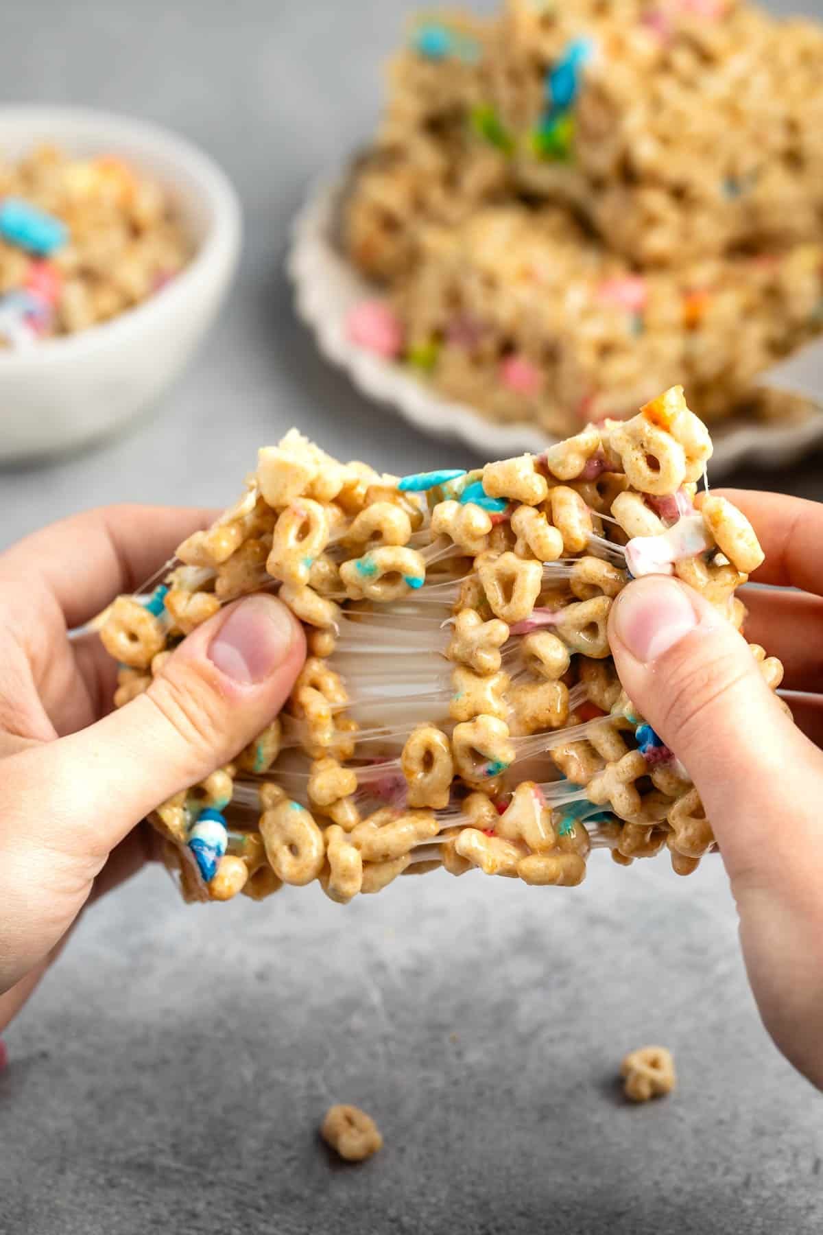 Rice Krispie treats made from lucky charms being pulled apart with hands.