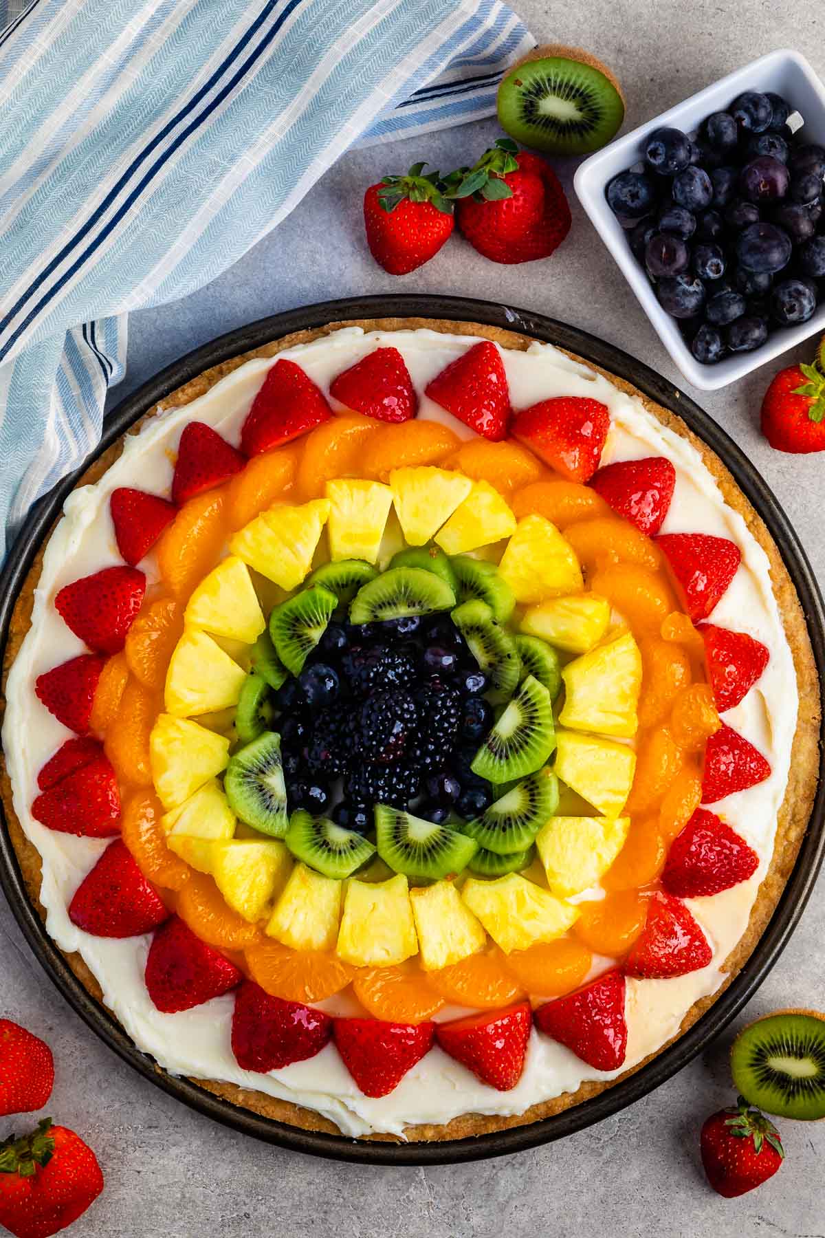 all types of fruit laid in rainbow order on a circular piece of dough.