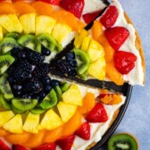 all types of fruit laid in rainbow order on a circular piece of dough.