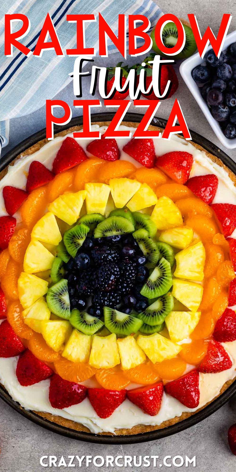 all types of fruit laid in rainbow order on a circular piece of dough with words on the image.