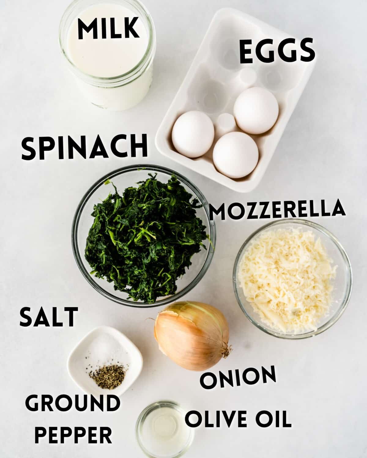 ingredients in spinach quiche laid out on a marble counter.