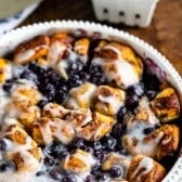 cinnamon roll bake with blueberries baked in a white pan.