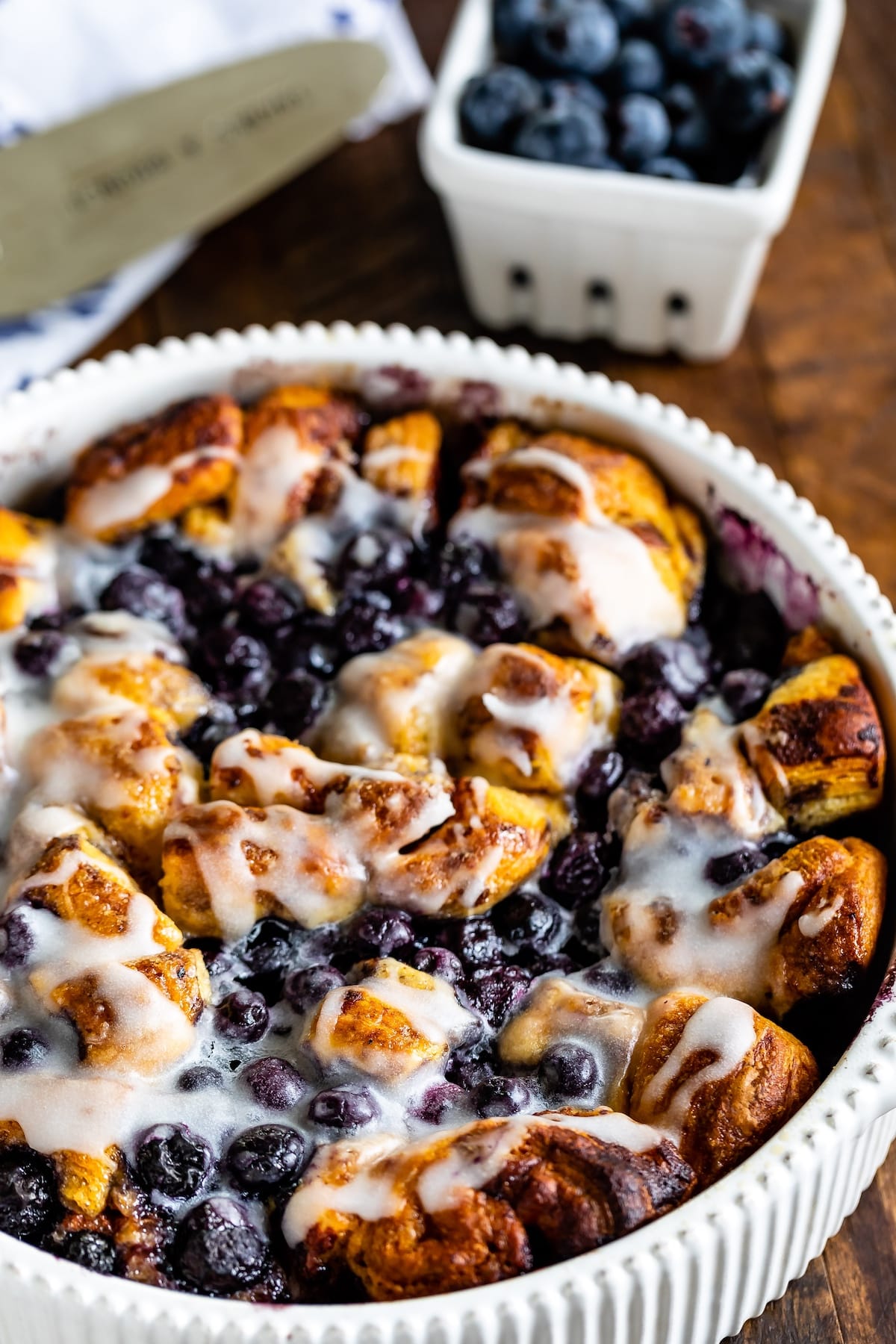 cinnamon roll bake with blueberries baked in a white pan.