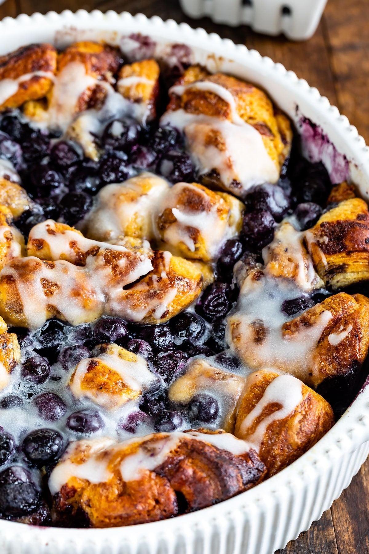 cinnamon roll bake with blueberries baked in a white pan.