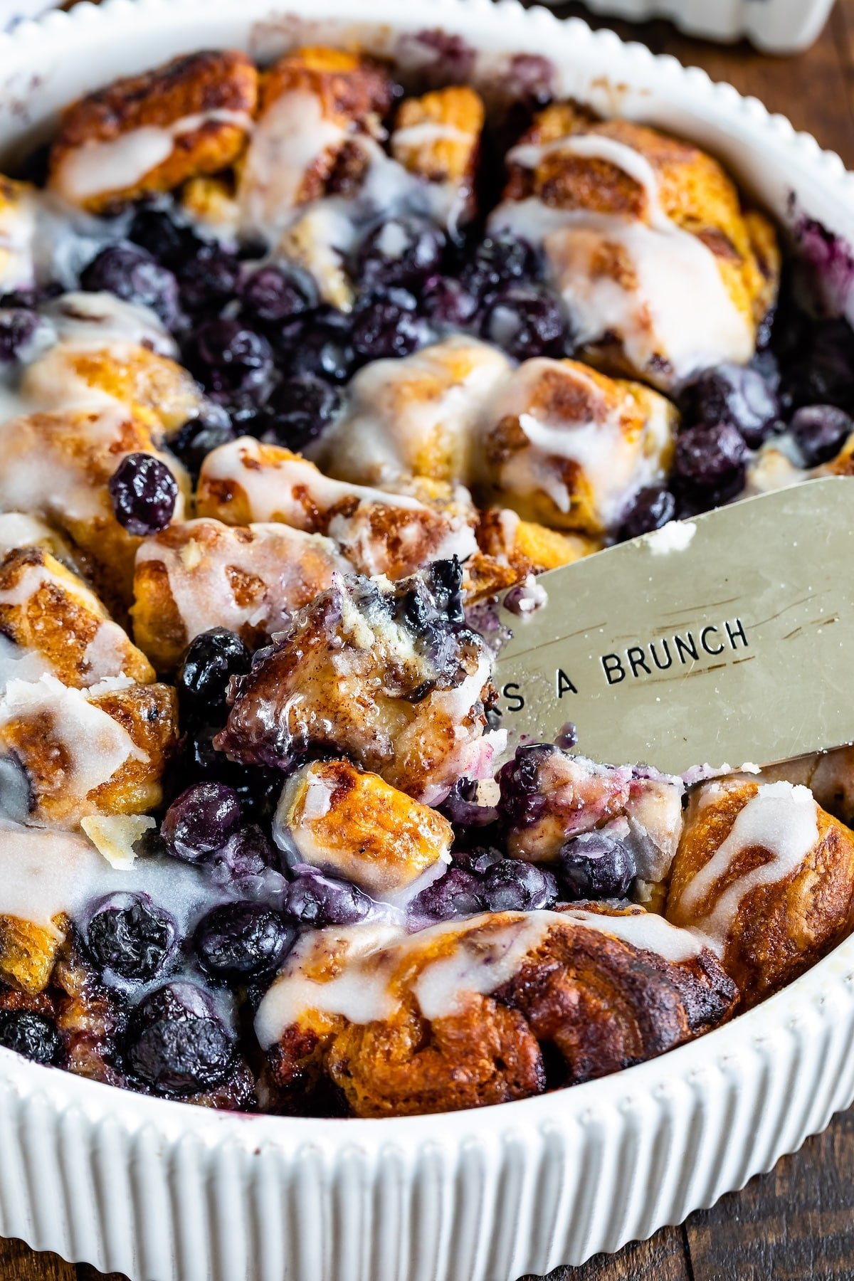 cinnamon roll bake with blueberries baked in a white pan.