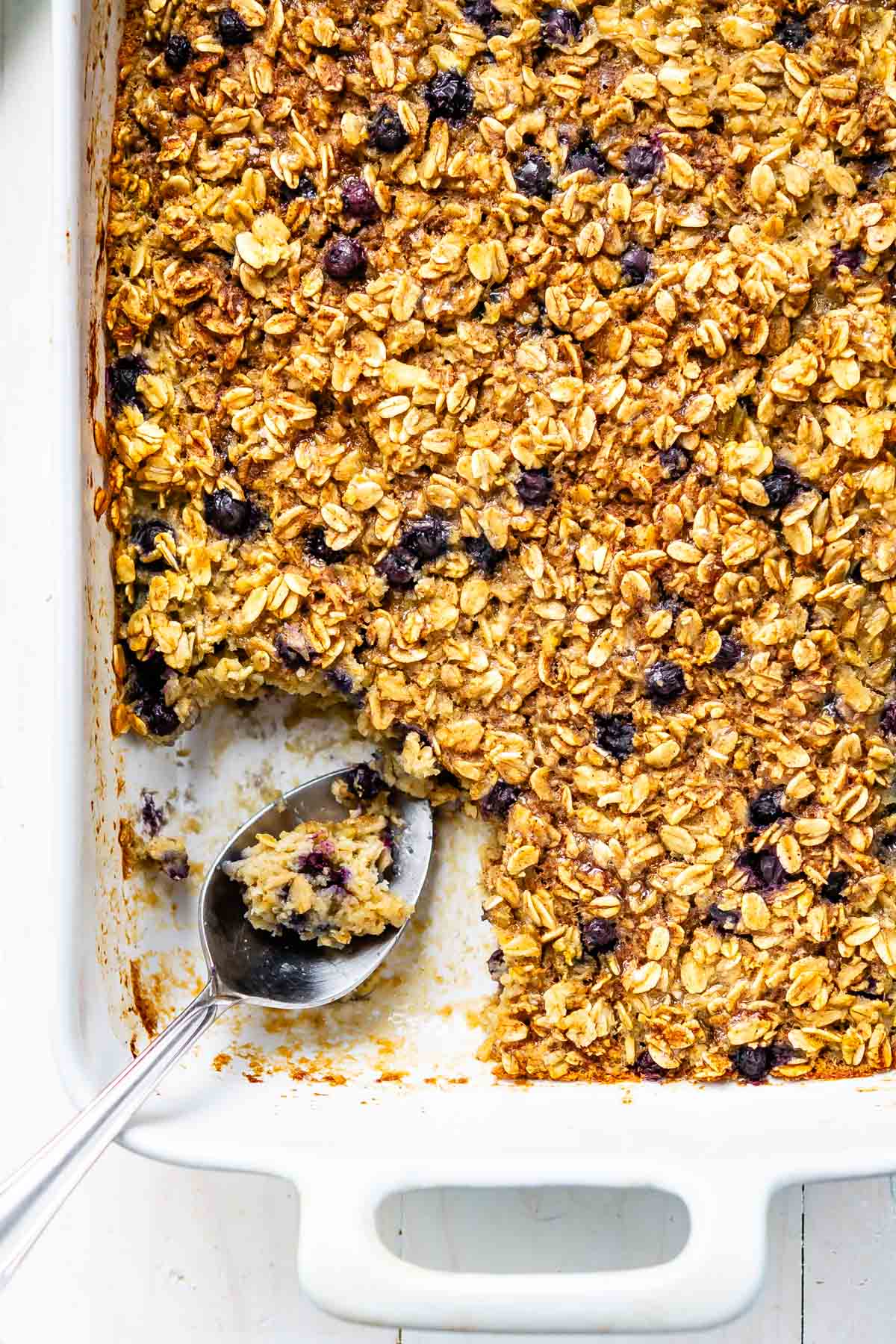 oatmeal baked in a white pan with a large silver spoon in the pan.